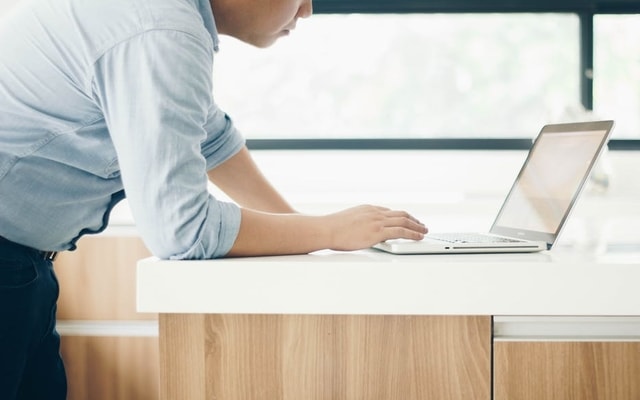 man leaning over laptop computer